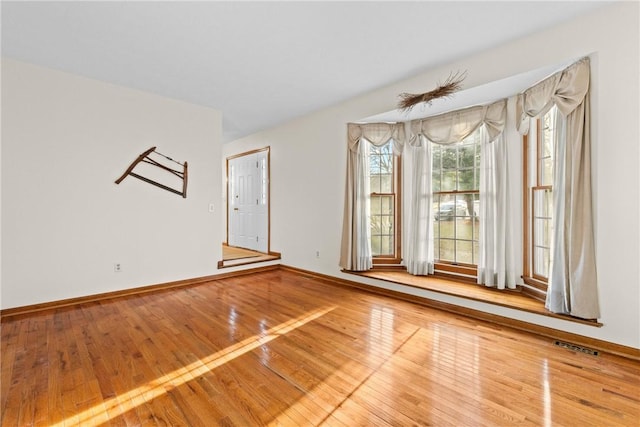 unfurnished room featuring visible vents, baseboards, and hardwood / wood-style flooring