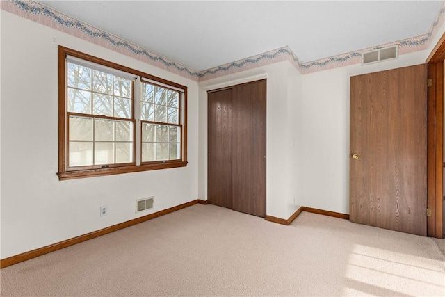 unfurnished bedroom with visible vents, multiple windows, and carpet