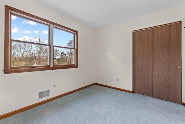 unfurnished bedroom featuring carpet, visible vents, a closet, and baseboards