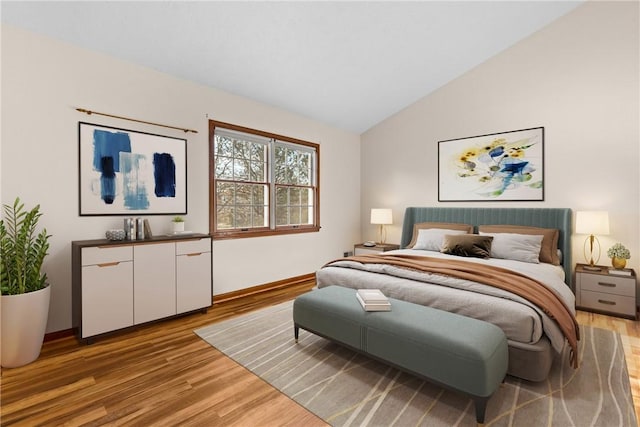 bedroom with baseboards, light wood-style floors, and vaulted ceiling