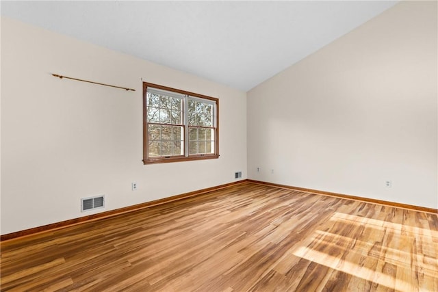 unfurnished room with vaulted ceiling, baseboards, visible vents, and light wood finished floors