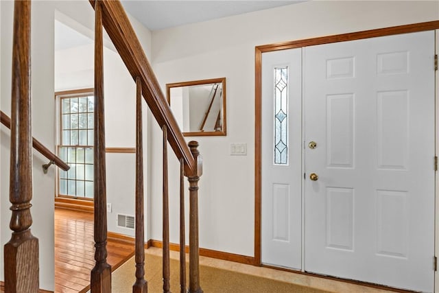 entryway featuring visible vents, stairway, baseboards, and wood finished floors