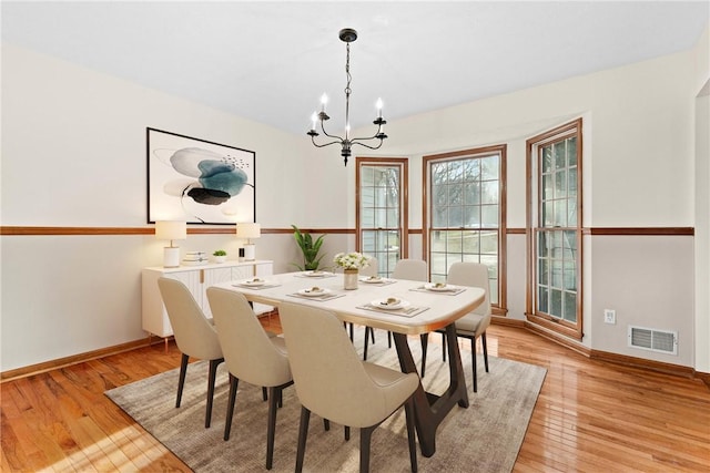 dining space with visible vents, baseboards, a chandelier, and light wood finished floors