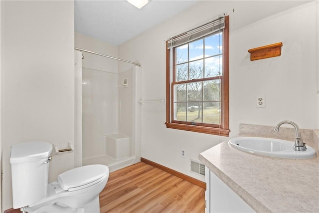 bathroom with visible vents, toilet, wood finished floors, a shower, and baseboards