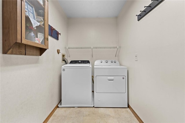 laundry area with baseboards, separate washer and dryer, and laundry area