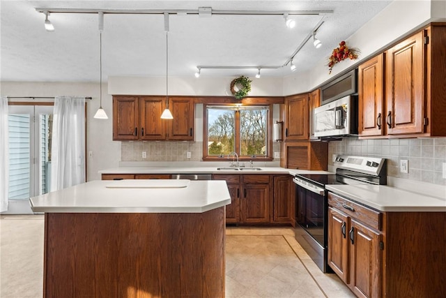 kitchen featuring light countertops, brown cabinets, appliances with stainless steel finishes, and a sink