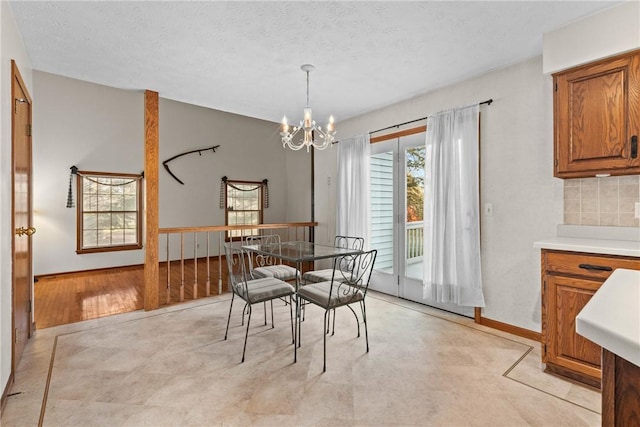 dining room featuring baseboards, a textured ceiling, and a chandelier