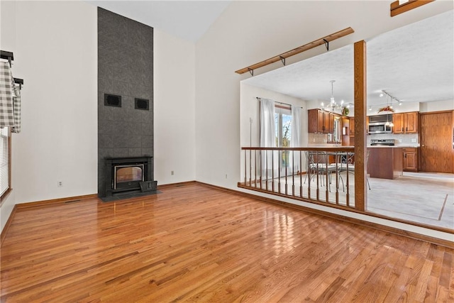 unfurnished living room featuring baseboards, visible vents, light wood finished floors, and a chandelier