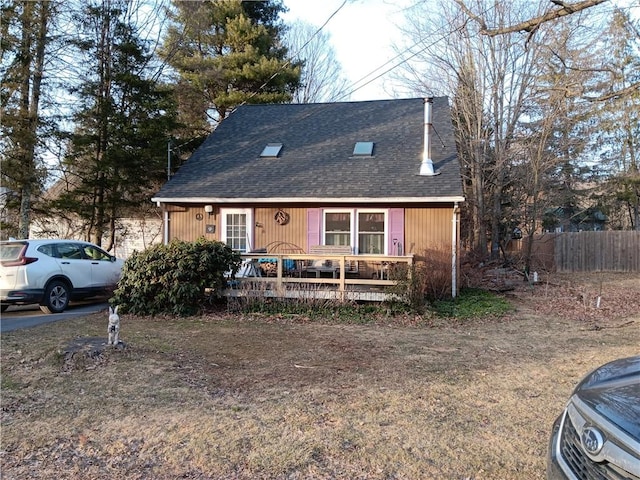 view of front of house with fence, a deck, and a shingled roof