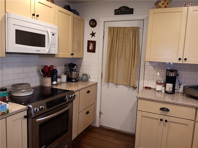 kitchen featuring dark wood-type flooring, light stone counters, tasteful backsplash, stainless steel range with electric cooktop, and white microwave