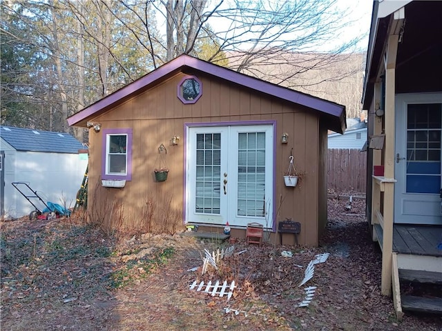 view of outdoor structure with french doors, an outdoor structure, and fence