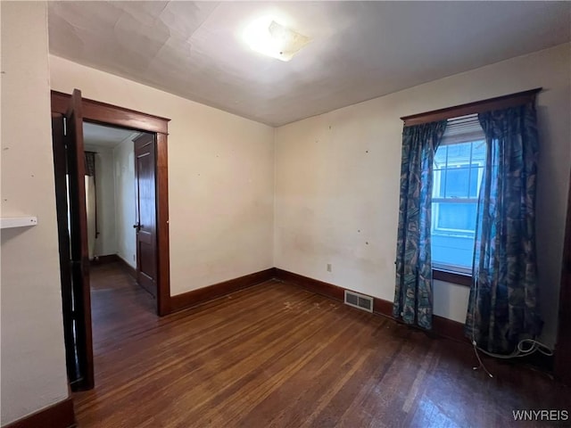 spare room with visible vents, baseboards, and wood finished floors