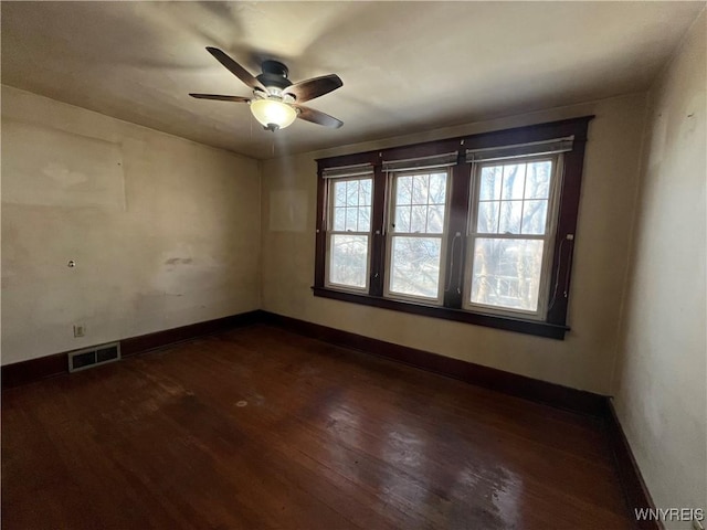 unfurnished room featuring dark wood finished floors, visible vents, baseboards, and ceiling fan