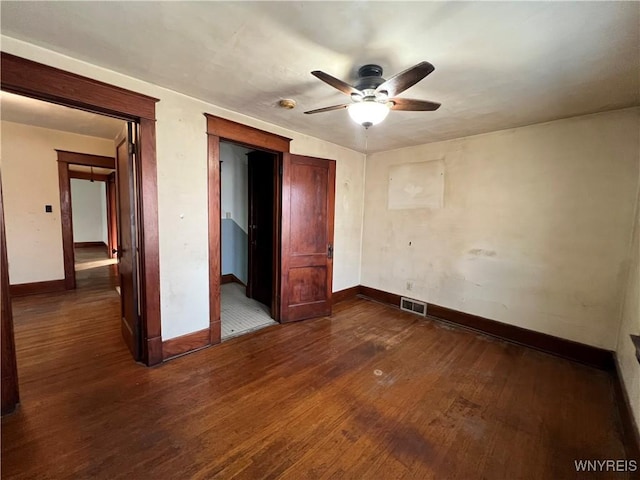 unfurnished bedroom featuring a ceiling fan, dark wood-type flooring, baseboards, and visible vents