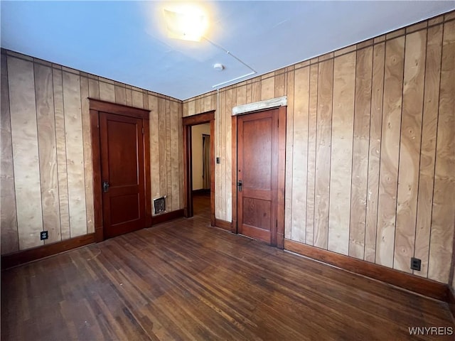 unfurnished bedroom with wooden walls, wood finished floors, and baseboards