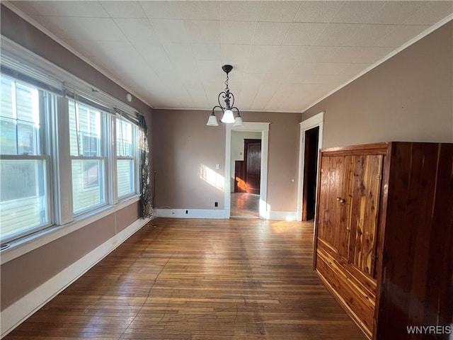 unfurnished dining area featuring baseboards, ornamental molding, and dark wood-style flooring