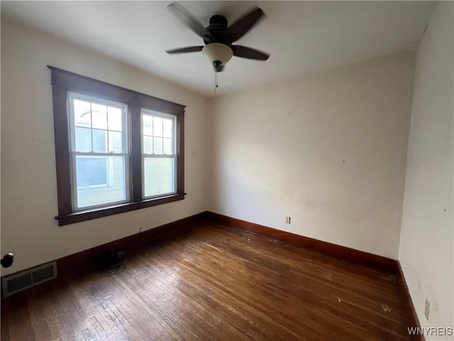 empty room with ceiling fan, dark wood-style floors, visible vents, and baseboards