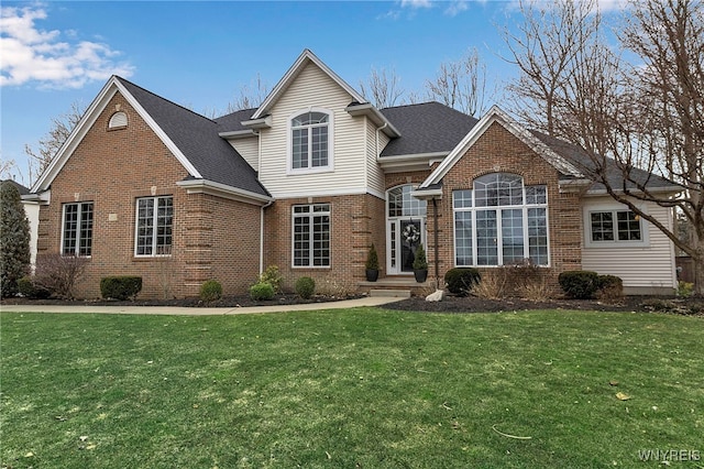 traditional home with brick siding, roof with shingles, and a front yard