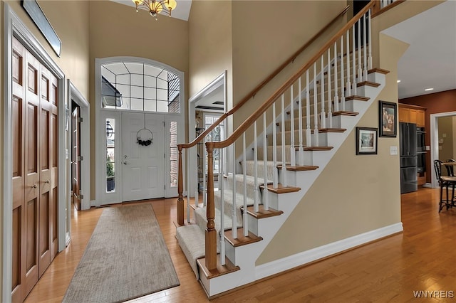 foyer entrance featuring plenty of natural light, light wood-style flooring, a high ceiling, and baseboards