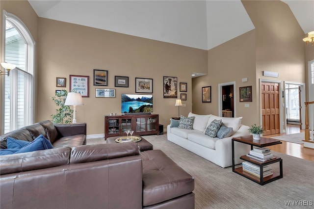 living area with a chandelier, baseboards, a towering ceiling, and carpet floors