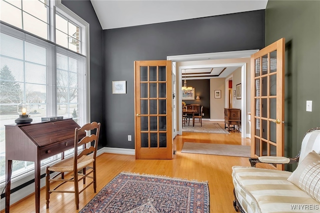 home office featuring a wealth of natural light, baseboards, light wood-style floors, and lofted ceiling