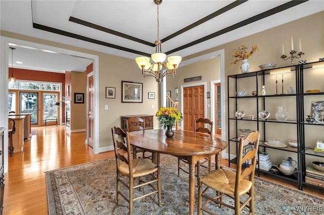 dining space with baseboards, french doors, a raised ceiling, a notable chandelier, and light wood-type flooring