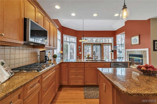 kitchen with a sink, appliances with stainless steel finishes, a peninsula, and a healthy amount of sunlight