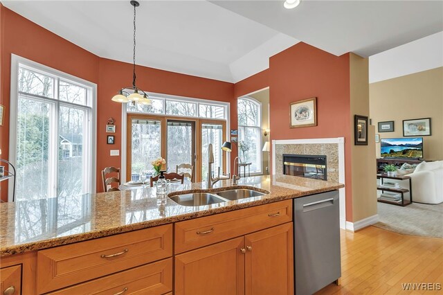 kitchen with a sink, plenty of natural light, open floor plan, light stone countertops, and dishwasher