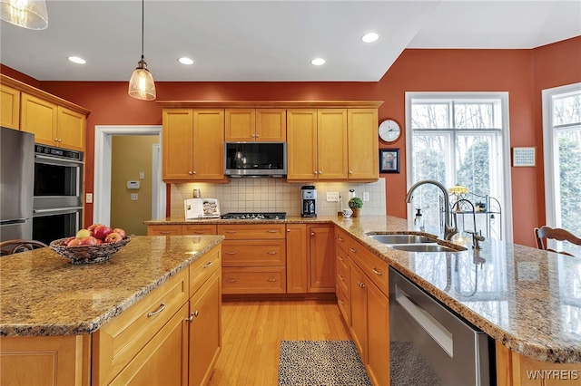 kitchen with a sink, light wood-style flooring, tasteful backsplash, and stainless steel appliances