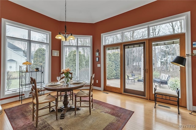 dining area featuring a chandelier, plenty of natural light, light wood-style flooring, and visible vents