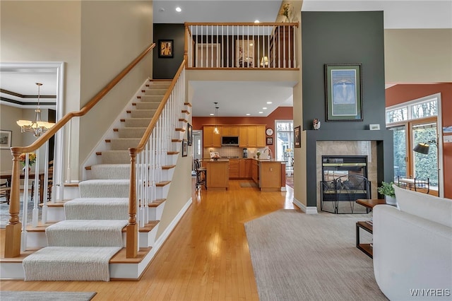 interior space with wood finished floors, a high ceiling, an inviting chandelier, a fireplace, and baseboards