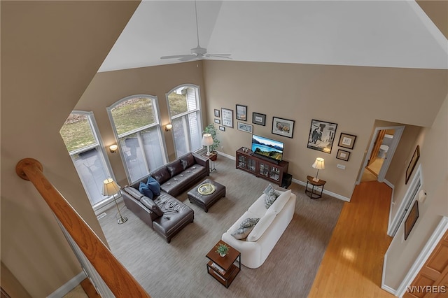 living area featuring baseboards, high vaulted ceiling, wood finished floors, and a ceiling fan