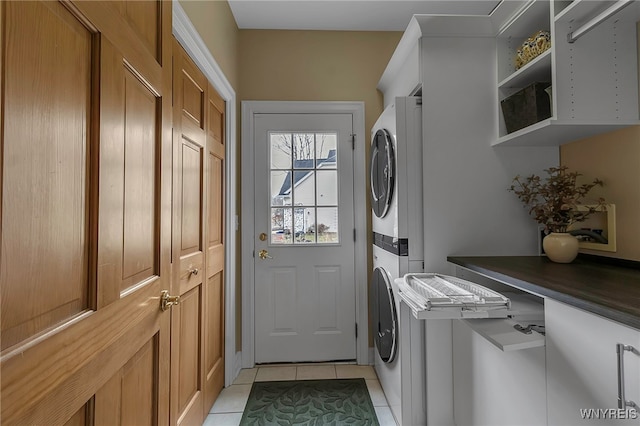 laundry room with light tile patterned flooring, cabinet space, and stacked washer and dryer