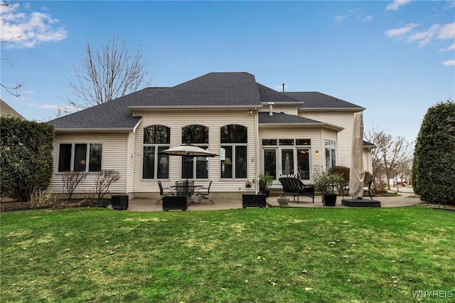 back of property featuring a yard, a shingled roof, and a patio area