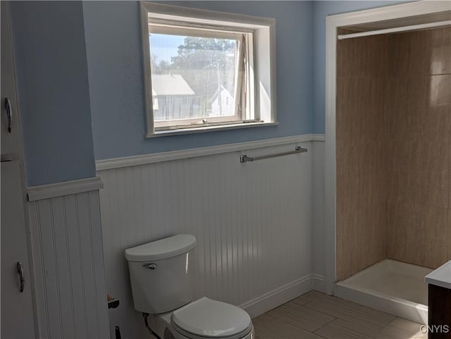 full bathroom with a shower stall, toilet, and wainscoting