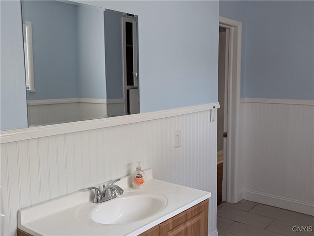 bathroom with vanity, wood finished floors, and wainscoting