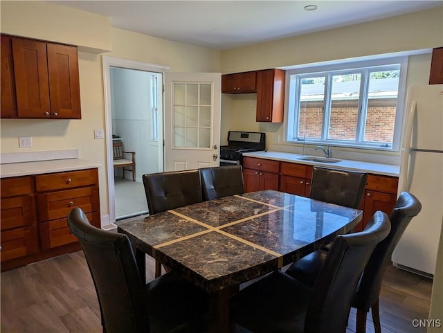 kitchen featuring stainless steel range with gas cooktop, freestanding refrigerator, dark wood-type flooring, and a sink