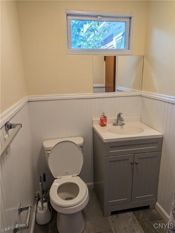 bathroom with a wainscoted wall, toilet, and vanity