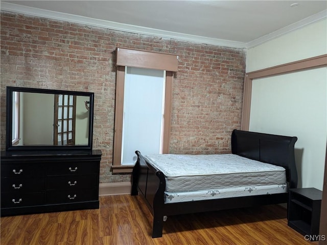 bedroom featuring baseboards, brick wall, wood finished floors, and crown molding