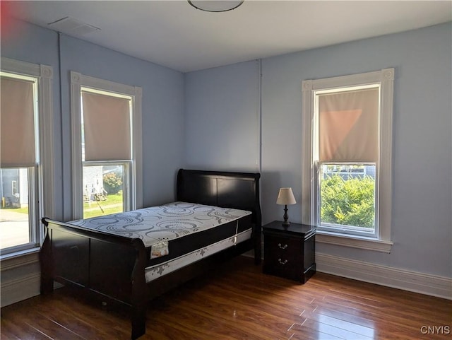 bedroom featuring visible vents, baseboards, and dark wood-style floors