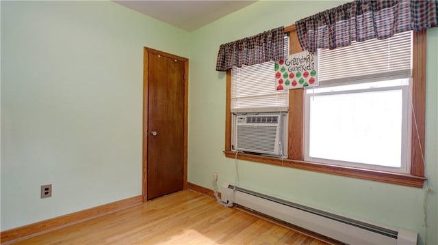 unfurnished room featuring light wood-style flooring, cooling unit, a baseboard heating unit, and baseboards