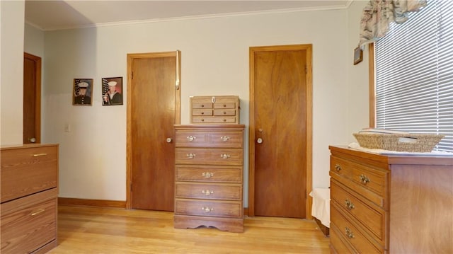 bedroom featuring baseboards, crown molding, and light wood-style floors