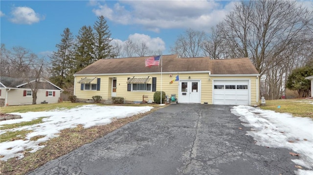 ranch-style home featuring aphalt driveway and a garage