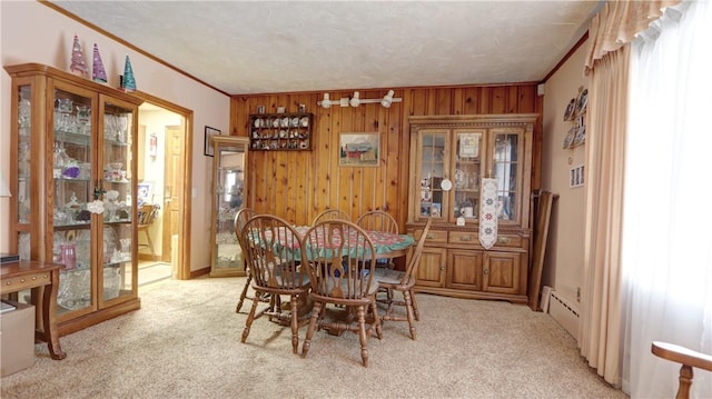 dining room featuring carpet, wood walls, and crown molding