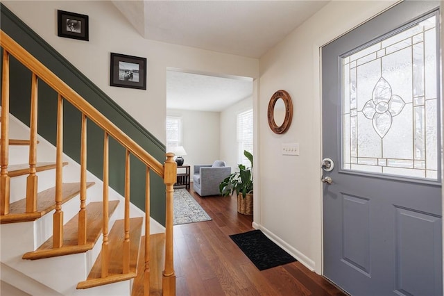 foyer with baseboards, dark wood finished floors, and stairs