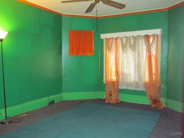 unfurnished room with crown molding, a ceiling fan, and baseboards