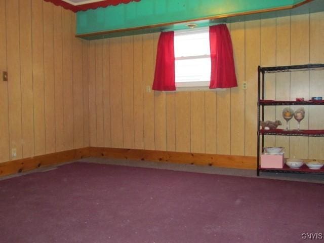 unfurnished room featuring wooden walls