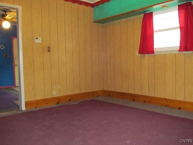 spare room featuring wooden walls and carpet floors