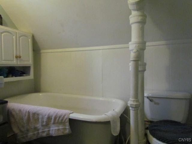 bathroom featuring toilet, a bathing tub, and wainscoting