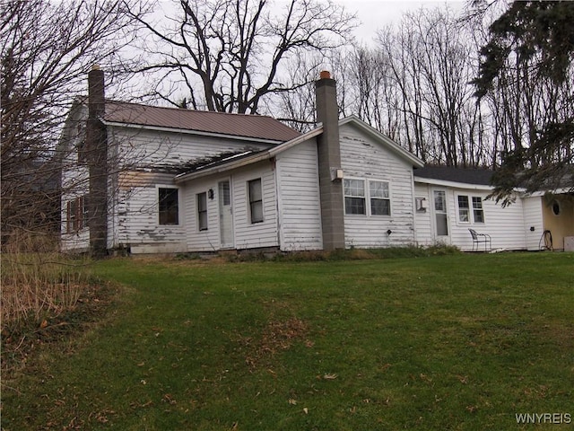 rear view of property featuring a lawn and a chimney